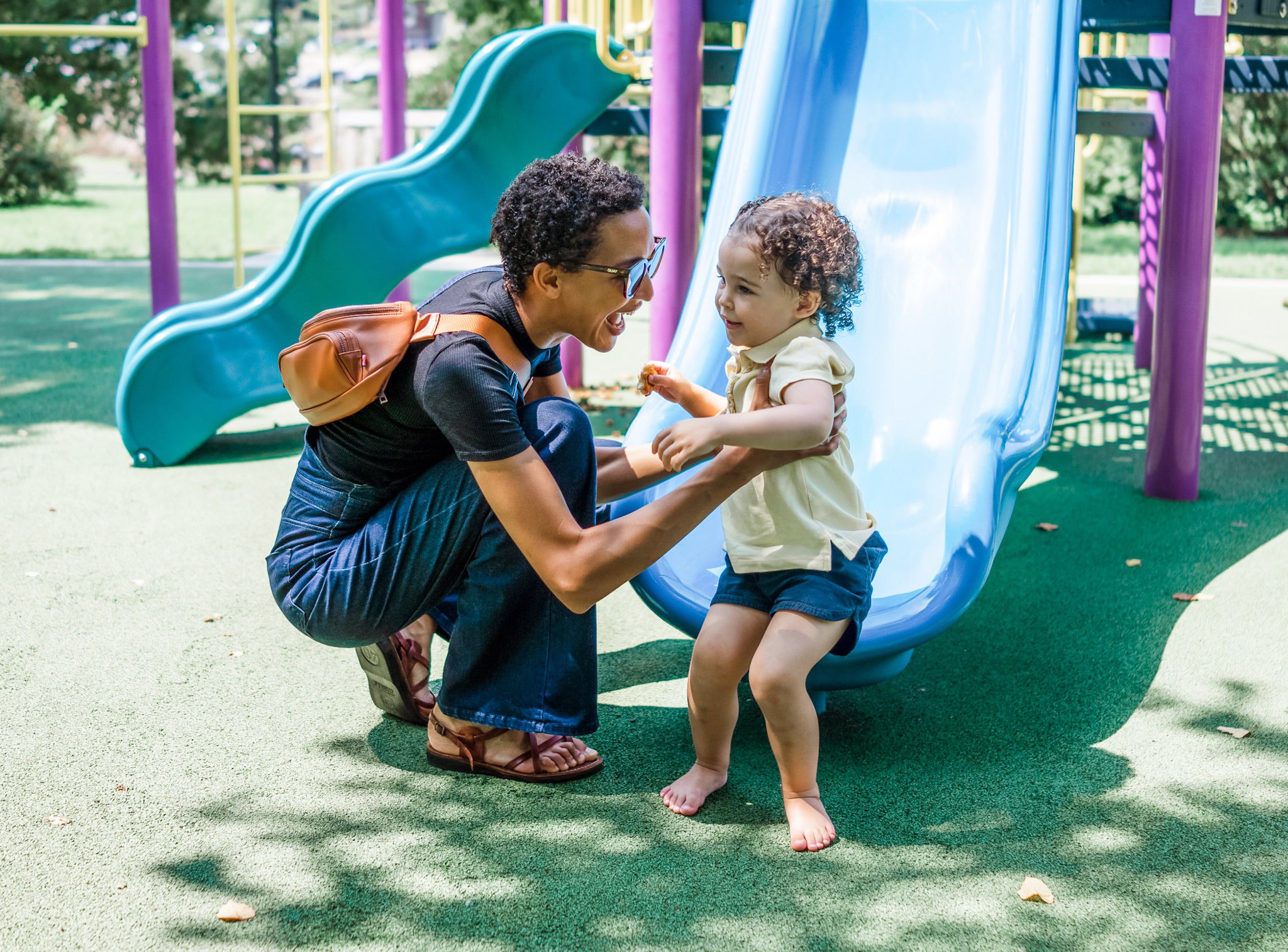 Mom with baby bag on her back at the park with toddler girl