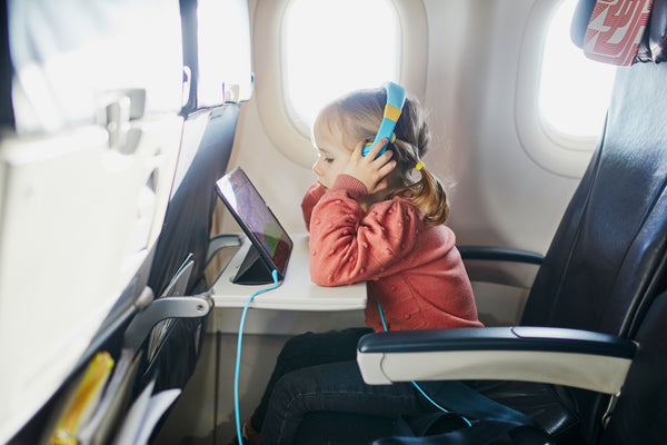 toddler girl watching ipad on plane while listening with her headphones