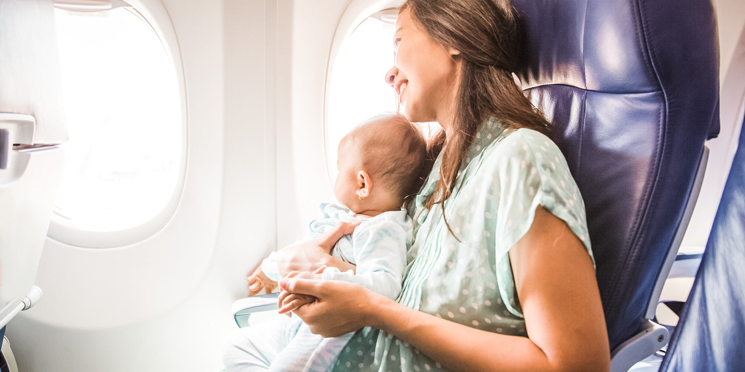 mom sitting with baby on airplane looking out window