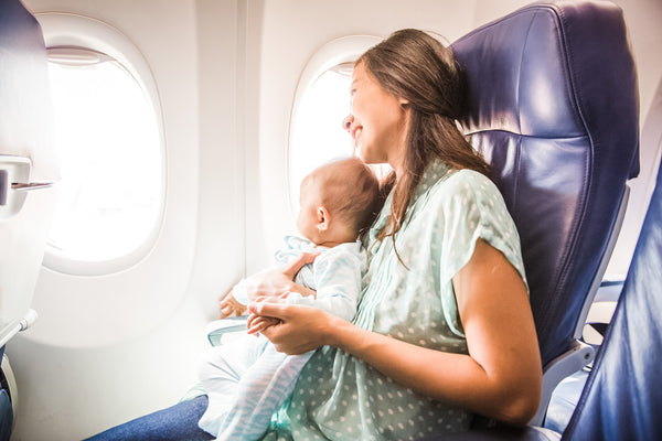 mom sitting with baby on airplane looking out window